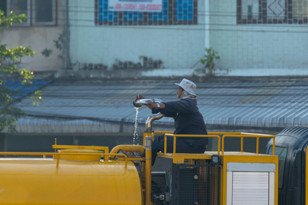 Bangkok, Thailand - November 21, 2015 : Unidentified Bangkok Metropolitan Administration worker working for watering the lawn on road by water tanker truck in Bangkok, Thailand.のeditorial素材