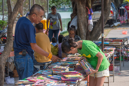 Bangkok, Thailand - April 16, 2016 : Thai book shop with old man seller and girl buyer at street market.のeditorial素材