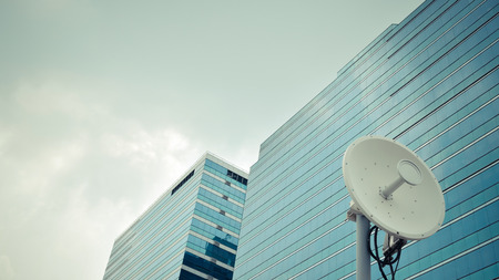 Satellite dish and building with blue sky background , process in vintage styleの写真素材