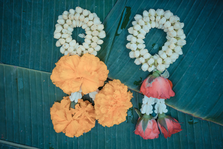 Beautiful garland jasmine and rose and calendula flower on green banana leaf , process in vintage styleの写真素材