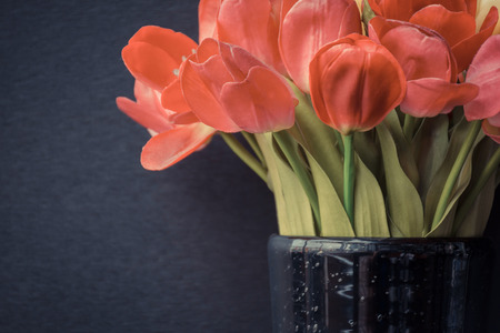 Beautiful tulips flower red color in black vase on black background , process in vintage styleの写真素材