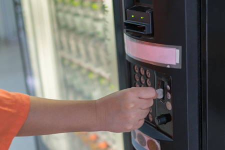 Hand of women put a coin into water drink vending machine