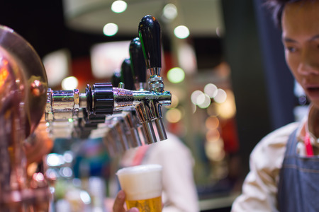 Bangkok, Thailand - May 28, 2016 : Unidentified barman or bartender pouring a draught lager beer from beer tap on counter for serving in a restaurant or pub.のeditorial素材