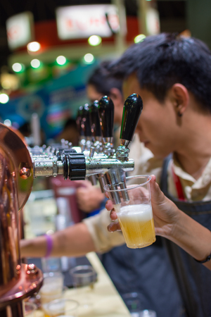 Bangkok, Thailand - May 28, 2016 : Unidentified barman or bartender pouring a draught lager beer from beer tap on counter for serving in a restaurant or pub.のeditorial素材