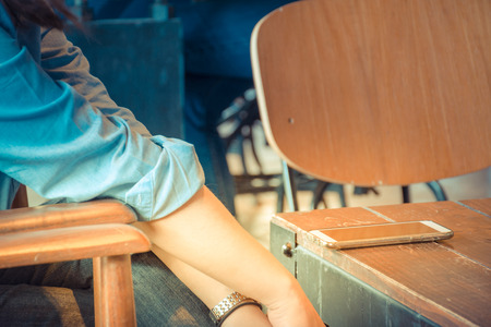 Mobile phone and women on wood table in coffee shop or restaurant , process in vintage styleの写真素材