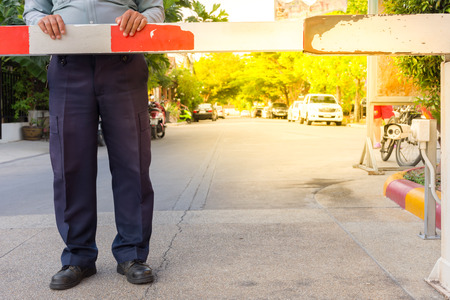 Security guard with barrier gate for access control at gateway , process in soft orange sun light...