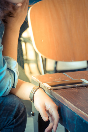 Mobile phone and women on wood table in coffee shop or restaurant , process in vintage styleの写真素材
