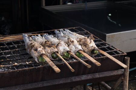 Salt-Crusted Grilled Snakehead fish grill on charcoal stove at marketの写真素材