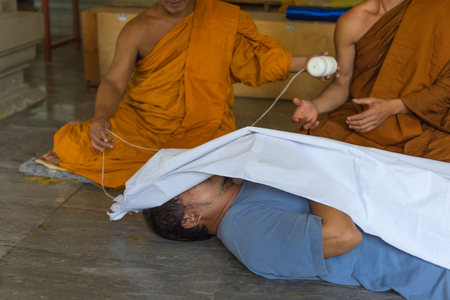 Bangkok, Thailand - June 19, 2016 : Feint requiem is a ceremony for protect to dead. Use shroud cover on a man by monk in Thai templeのeditorial素材