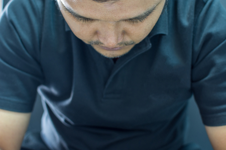 Asia man in black polo shirt have a depression gesture with stress and sadness concept on black background dark styleの写真素材