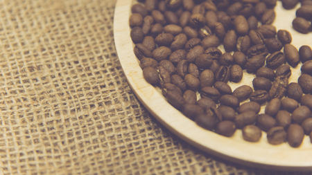 Coffee beans and roasted coffee beans in wooden tray on the sack clothの写真素材