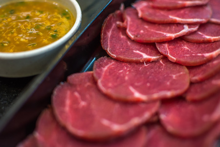 Beef raw meat slides on dish with barbecue sauce at BBQ. yakiniku grill buffet restaurant