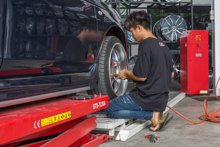 Bangkok, Thailand - March 9, 2017 : Unidentified car mechanic or serviceman disassembly and checking a car alloy chrome wheel for fix and repair suspension problem at car garage or repair shopのeditorial素材