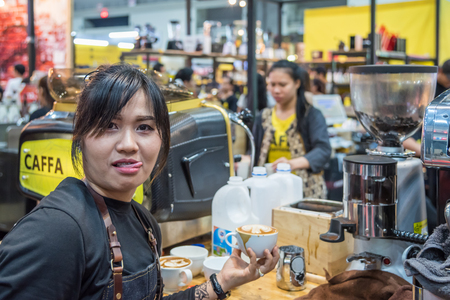 Bangkok, Thailand - March 19, 2017 : Unidentified woman barista pouring latte froth to make a coffee latte art into the white coffee cup for serve to customers in the coffee shop.のeditorial素材