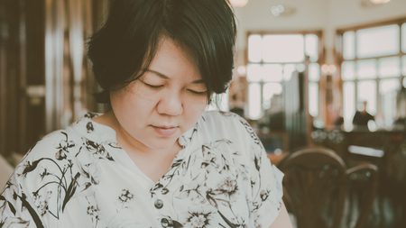 Asian women 40s white skin in white and black dress have a looking and reading a menu or read something in a coffee shop cafe vintage styleの写真素材