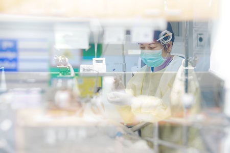 Asian women 40s years old in gown coat is a patient relative taking care of the CRE. or VRE. infected elder patient 80s years old on bed in the hospital.の写真素材