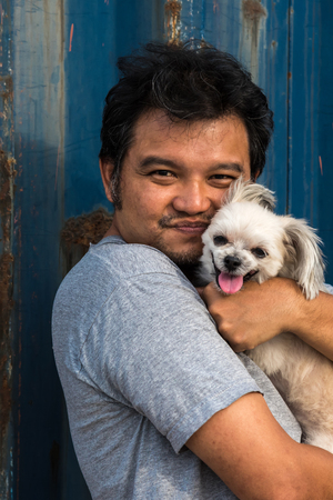 Asia man and dog happy smile hugging her pat is a dog so cute mixed breed with Shih-Tzu, Pomeranian...