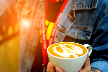 Barista pouring latte froth to make a coffee latte art into the white coffee cupの写真素材