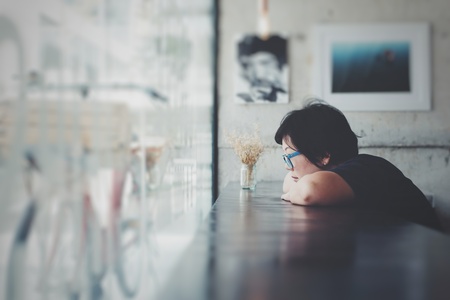 Asia women 40s white skin in black dress with eye glasses have a doubt and think gesture in a coffee shop cafeの写真素材