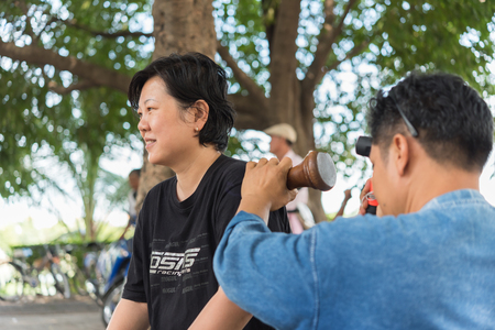 Bangkok, Thailand - July 28, 2017 : Unidentified Thai woman to take of service Thai massage by wooden hammer for treat aches and pains. The service comes in the outdoor garden.のeditorial素材