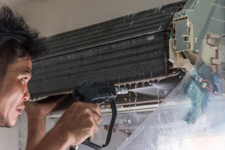 Bangkok, Thailand - July 22, 2017 : Unidentified worker to cleaning coil cooler of air conditioner by water for clean a dust on the wall in customer home when maintenance serviceのeditorial素材