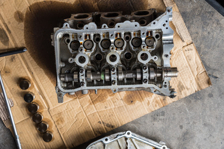 Disassembled car dirty engine close-up to engine parts and cylinder head at car garage