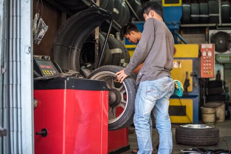 Bangkok, Thailand - September 1, 2017 : Unidentified car mechanic or serviceman disassembly and checking a car alloy chrome wheel for fix and repair suspension problem at car garage or repair shopのeditorial素材