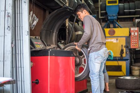 Bangkok, Thailand - September 1, 2017 : Unidentified car mechanic or serviceman disassembly and checking a car alloy chrome wheel for fix and repair suspension problem at car garage or repair shopのeditorial素材