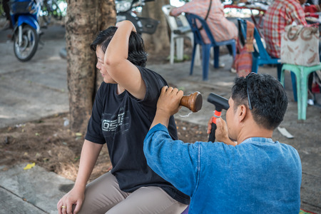 Bangkok, Thailand - July 28, 2017 : Unidentified Thai woman to take of service Thai massage by wooden hammer for treat aches and pains. The service comes in the outdoor garden.のeditorial素材