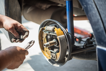 Car mechanic or serviceman checking a drum brake and asbestos brake pads it's a part of car use for stop the car for safety at rear wheel this a new spare part for repair at car garageの写真素材