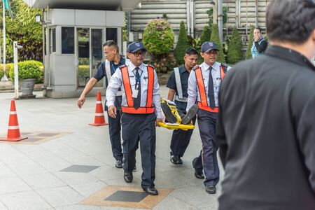 Bangkok, Thailand - November 30, 2017 : Many working people preparedness for fire drill or other disaster by move injury patient on spine board at office in Bangkok Thailandのeditorial素材