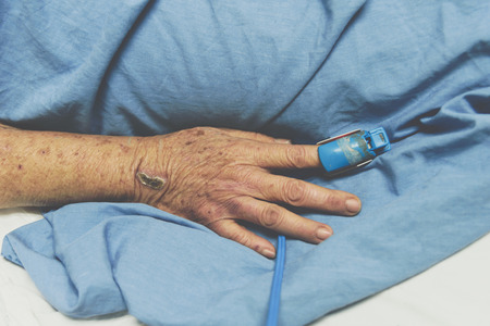 Patient in the hospital with pulse gauge for heartbeat measuring and blood pressure on a patient elderly fingerの写真素材