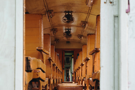 Inside of old public Thai railway train cabin with seats, handrails, fan and interior in vintage style service for passenger transportの写真素材