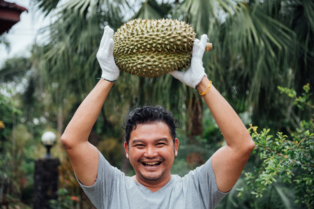 Asian man farmer holding Durian is a king of fruit in Thailand and asia fruit have a spikes shell and sweet can buy at Thai street food and fruit market at agriculture farmの写真素材