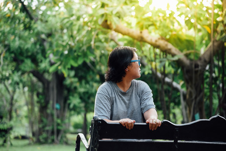 Asian woman 40s plump body with glasses happy sitting for relax in a green parkの写真素材
