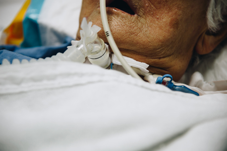 Patient asian elder women 80s do tracheostomy use ventilator for breathing help on bed in the hospital.の写真素材