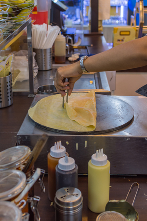 Bangkok, Thailand -  June 5, 2016 : Unidentified chef cooking a crepe is a sweet food for sale at Thai street dessert food market.のeditorial素材