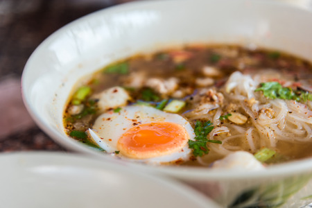 Spicy tom yum noodle with pork and egg for sale at Thai street food market or restaurant in Thailand