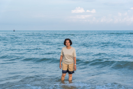 Asian elderly woman 60s with curly hair happy travel and relax at sea and beach when vacation travel for relaxの写真素材