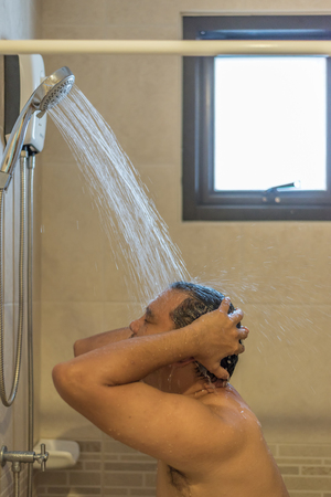 Asian man 40s showering in bathroom for clean a body and relax by bare and water drops from shower to the head and all bodyの写真素材