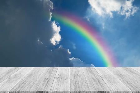 Cloudscape rainbow of natural sky with blue sky and white clouds and colorful rainbow in the sky with wood table or terrace use for wallpaper backgroundの写真素材