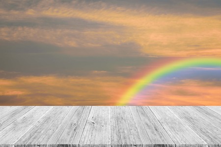 Cloudscape rainbow of natural sky with red sky and white clouds and colorful rainbow in the sky with wood table or terrace use for wallpaper backgroundの写真素材