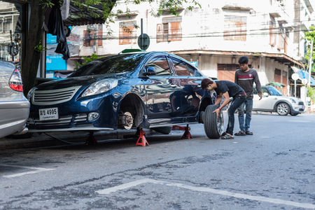 Bangkok, Thailand - September 1, 2017 : Unidentified car mechanic or serviceman disassembly and checking a car alloy chrome wheel for fix and repair suspension problem at car garage or repair shopのeditorial素材