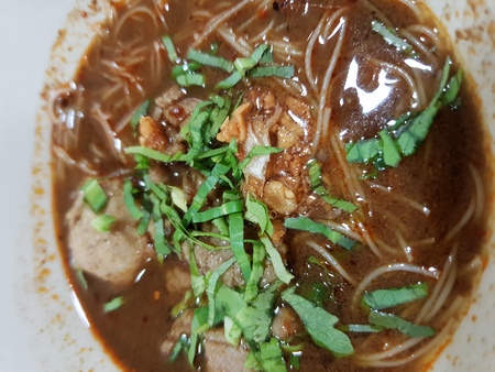 Braised beef clear noodle with meat balls soup stew (Ekaehla meat) with vegetable in bowl for sale at Thai street food market or restaurant in Thailandの写真素材
