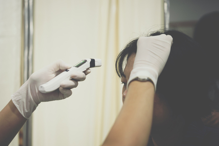 Thai woman health check measure fever levels by digital infrared thermometer every year at hospital by the Ministry of Health.の写真素材