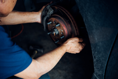 Car mechanic or serviceman checking a disc brake and asbestos brake pads it's a part of car use for stop the car for safety at front wheel this a new spare part for repair at car garageの写真素材