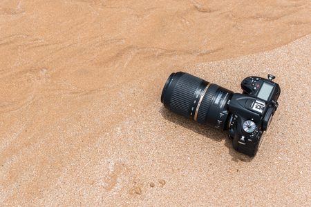 Rayong, Thailand - May 27, 2017 : Unidentified photographer demo waterproof DSLR camera with telephoto lens on beach it wet from water sea wave when travel and test using in the extreme environmentのeditorial素材