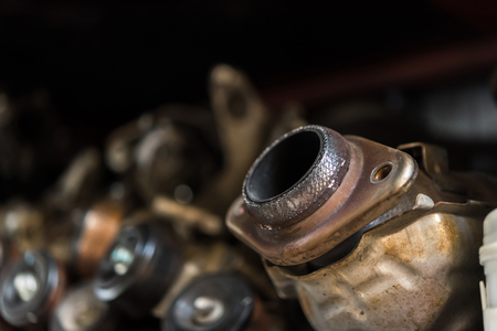 Disassembled car dirty engine close-up to engine parts and catalytic flange of muffler at car garage