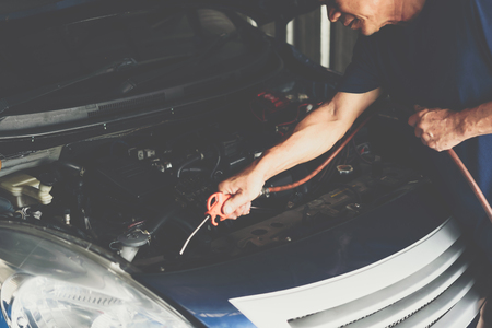 Car mechanic or serviceman cleaning the car engine after checking a car engine for fix and repair problem at car garage or repair shopの写真素材