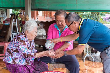 Ang Thong, Thailand - April 7, 2019 : Unidentified Asian people bathe respectation to elderly parents by water with jasmine, rose flower and aromatherapy in bowl in Songkran Festival (Thai New Year)のeditorial素材